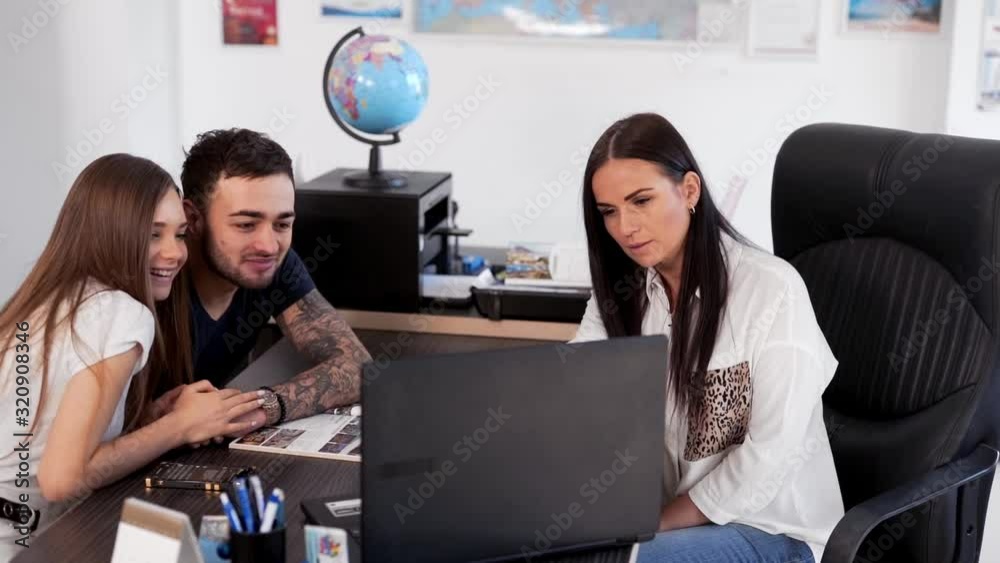 boyfriend and girlfriend looking at laptop travel options at travel agency boyfriend and girlfriend looking at laptop travel options at travel agency