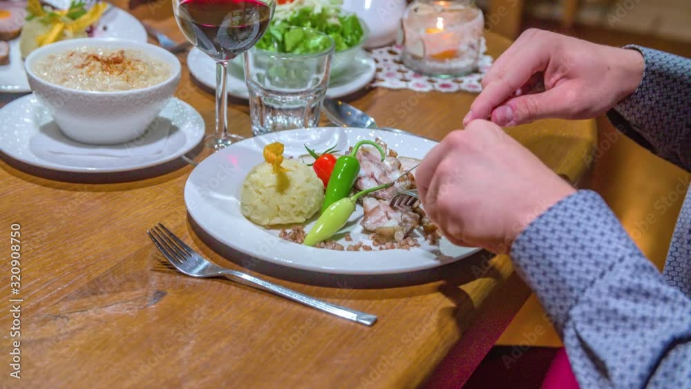 Man Picks up Knife and Fork and Cuts Meat on his Plate in Restaurant HANDHELD Man Picks up Knife and Fork and Cuts Meat on his Plate in Restaurant HANDHELD