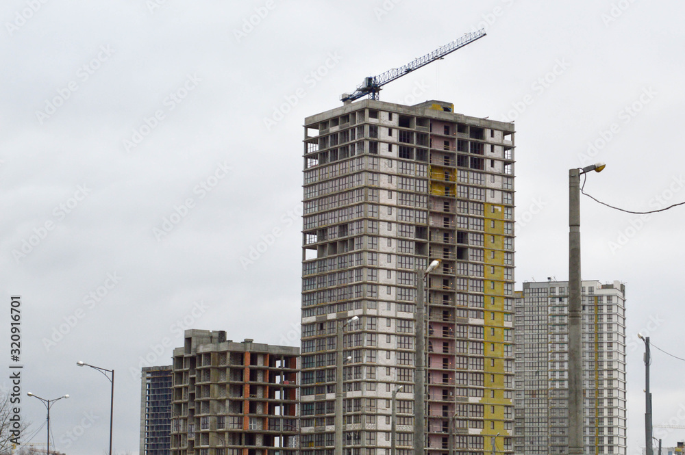 Construction of large modern monolithic frame houses, buildings using industrial construction equipment and large high cranes. Construction of the building in the new micro district of the city