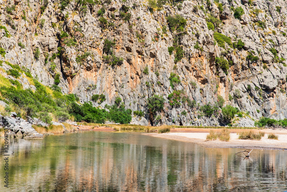 Naklejka premium Beautiful rocky mountains with a river in valley, landscape of wildlife, summer. Nature in Mallorca, Balearic Islands, Spain. River Torrent de Pareis between rocky mountains