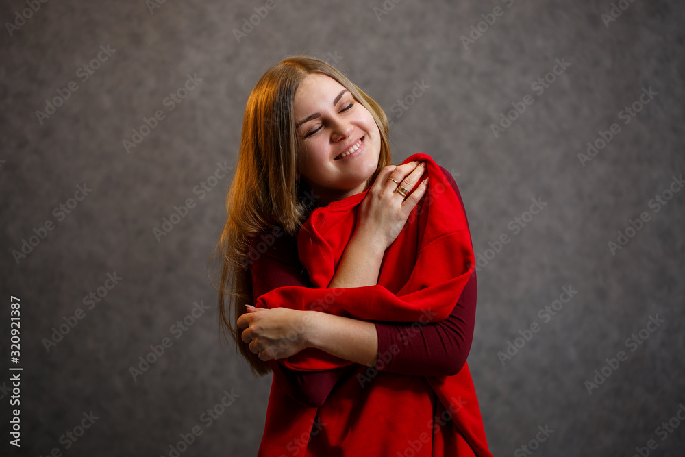 Girl tries on a red sweater on a gray background Girl tries on a red sweater on a gray background