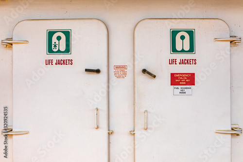 Close up of the doors of the life jacket compartment room on a passenger ferryboat in Canada. White aged surface with signs with explicative icons. photo