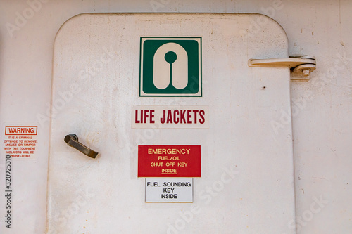 Close up of the door of the life jacket compartment room on a passenger ferryboat in Canada. White aged surface with signs with explicative icons. photo