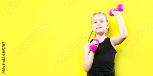 Theme sport and health. Beautiful caucasian child girl with pigtails posing on yellow background with smile. little athlete holding pink dumbbells. Banner for advertising  space for text copy space