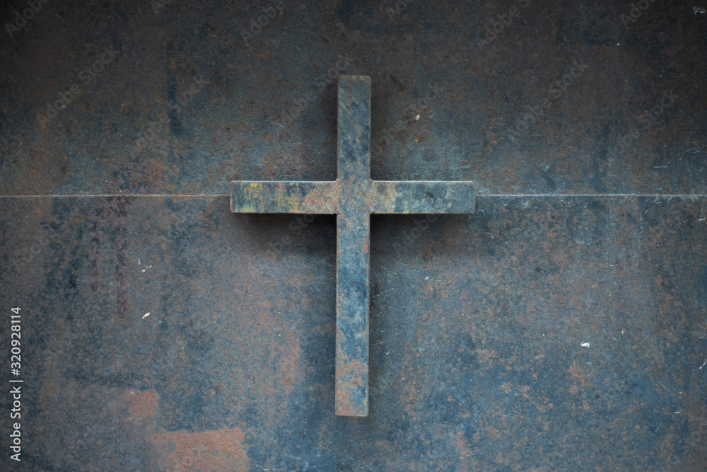 Metal cross sign hanging on the door. Old historical iron gate. Close-up.