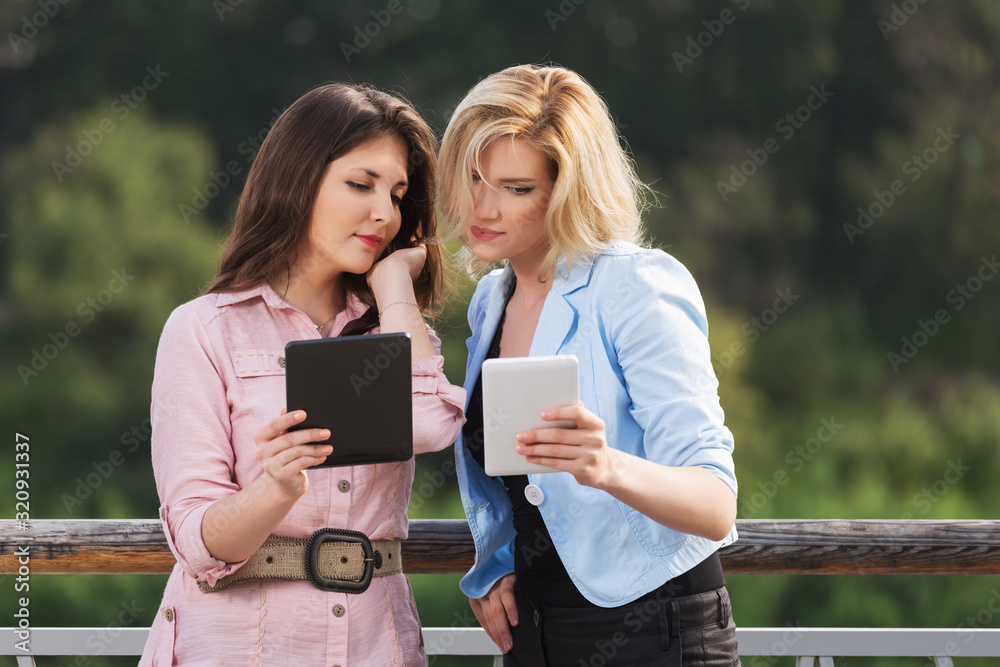 Two young fashion women using tablet computer Two young fashion women using tablet computer