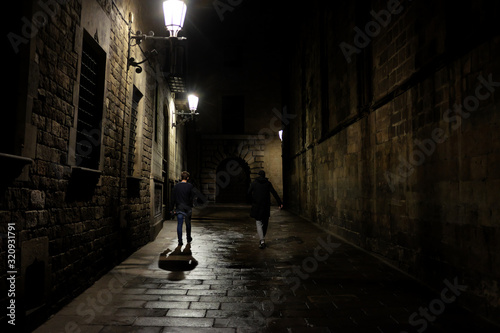 Barcelona, Spain - April 26: Two men walk in the light of the lamps down the night street on April 26, 2017 in Barcelona, Spain.