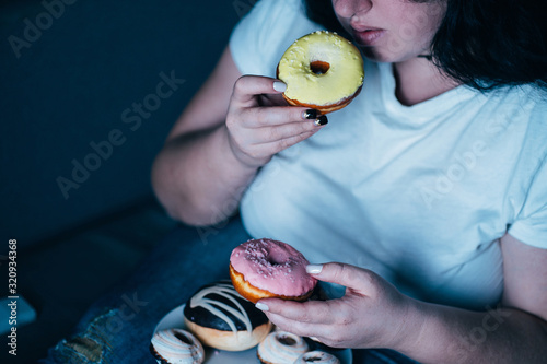Emotional eating, mental disorder, depression, loneliness, stress. Lonely woman eating sweets and watching tv late in the night. Nerve food