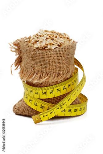 oat rolled cereals in full burlap sack with measure tape isolated on white background photo