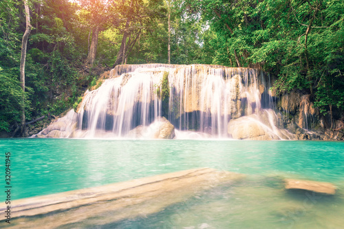 Waterfall, green forest in Erawan National Park, Thailand. Landscape with water flow, river, stream and rock at outdoor. Beautiful scenery of nature for tourist to tour, visit, relax in vacation. © DifferR