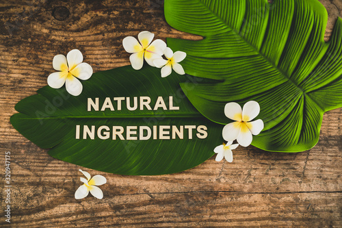 beauty industry and ethical vegan products, Natural Ingredients message on tropical banana leaf with monoi flowers
