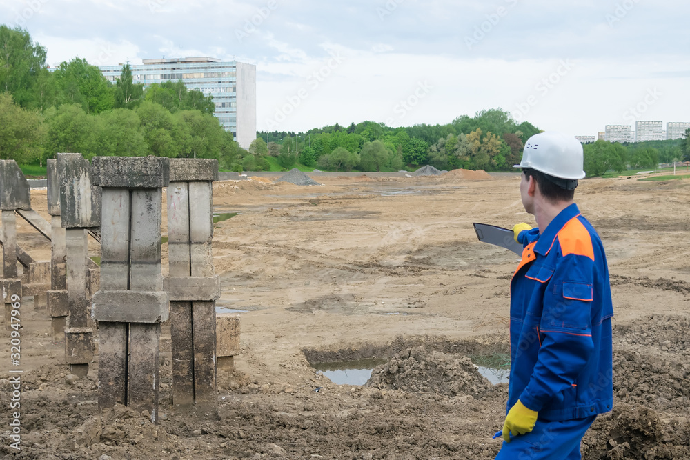 builder inspects a building site for an artificial lake
