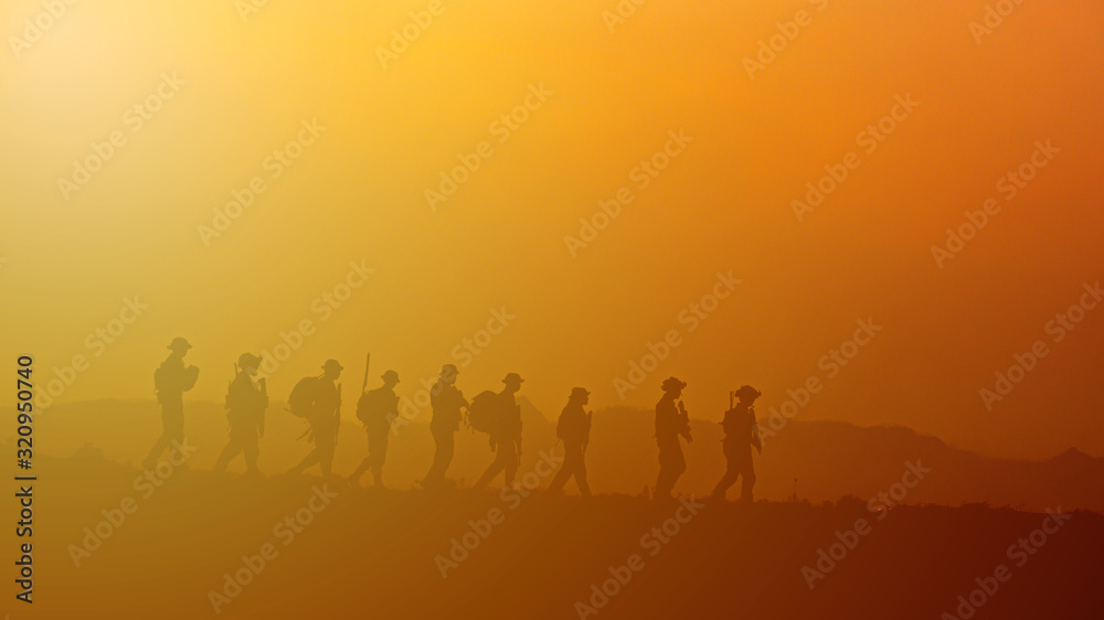Silhouette of military rangers with soldier on the top of mountain at sunset	
