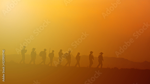 Silhouette of military rangers with soldier on the top of mountain at sunset   © AU USAnakul+