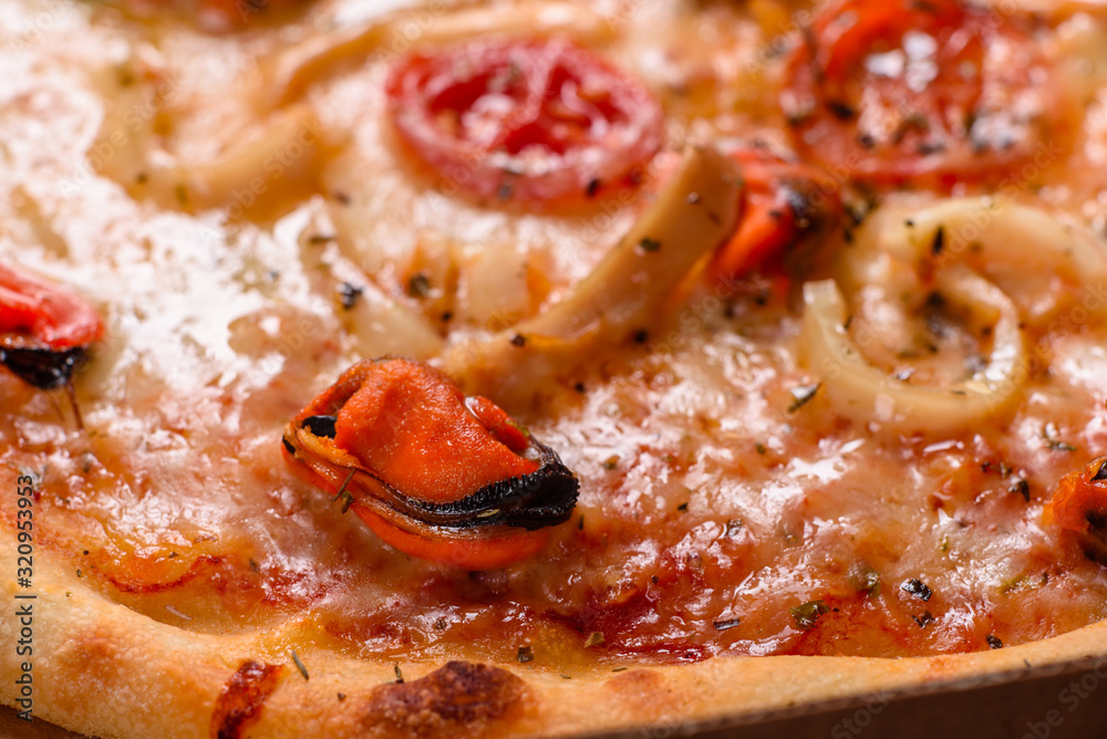 Tasty sliced pizza with seafood and tomato on a concrete background Tasty sliced pizza with seafood and tomato on a concrete background