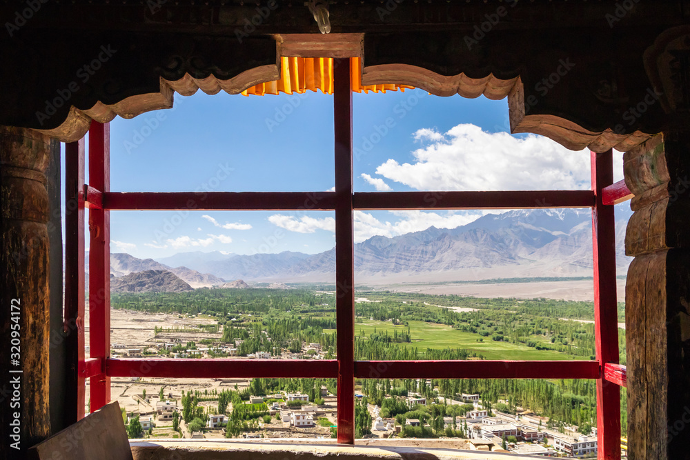 Fototapeta premium Amazing scenic view through the window of Thiksay Monastery or Thiksay Gompa to the green valley village of the Indus river, Leh Ladakh, Jammu and Kashmir, India.