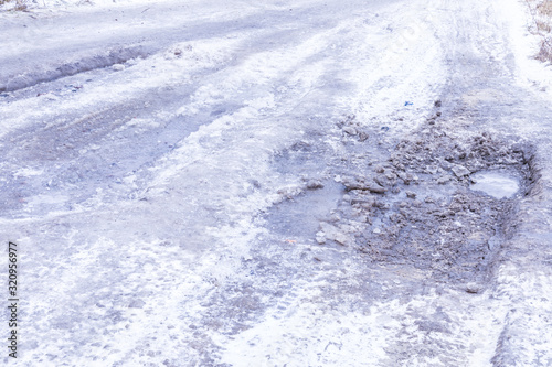 The bad asphalt winter road or way with ice, snow, puddles, pools, mud and slush © Майджи Владимир