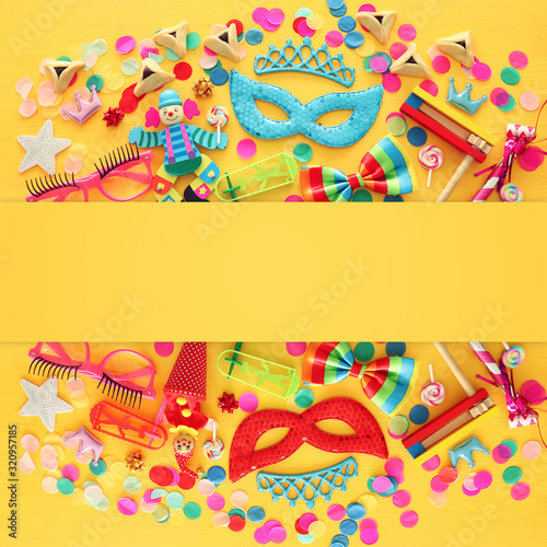 Purim celebration concept (jewish carnival holiday) over yellow wooden background. Top view, Flat lay