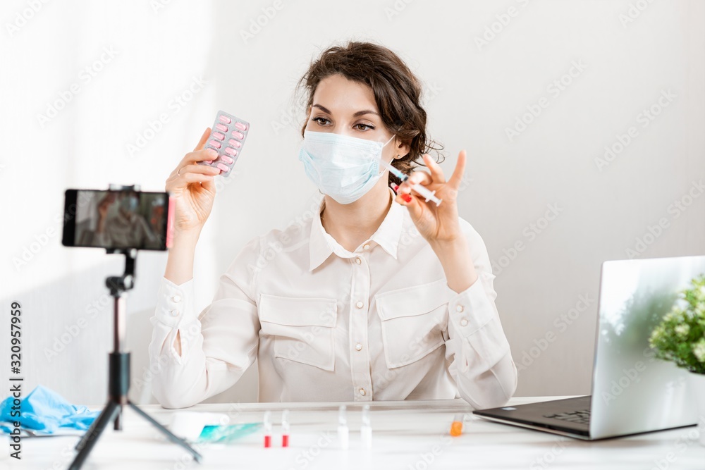 Influencer Girl blogger in medical mask talks about coronavirus. Woman recording video blog tells how to protect yourself from 2019-nСov. Bloger talks mers-cov how to use of alcohol wipes, thermometer
