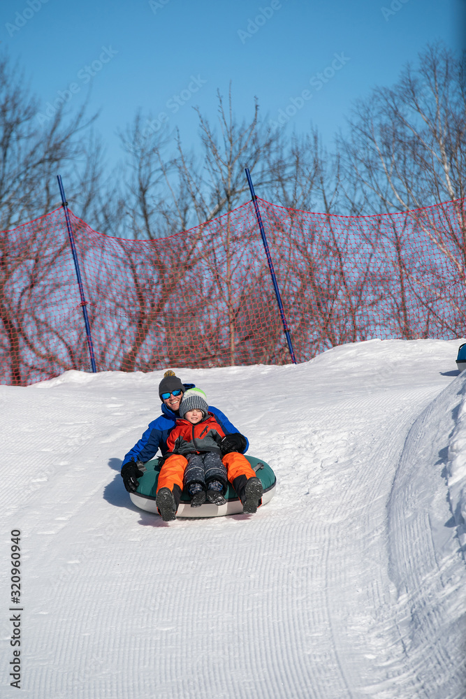 Father and son snow tubing in the winter in Canada