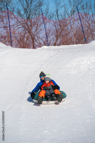 Father and son snow tubing in the winter in Canada