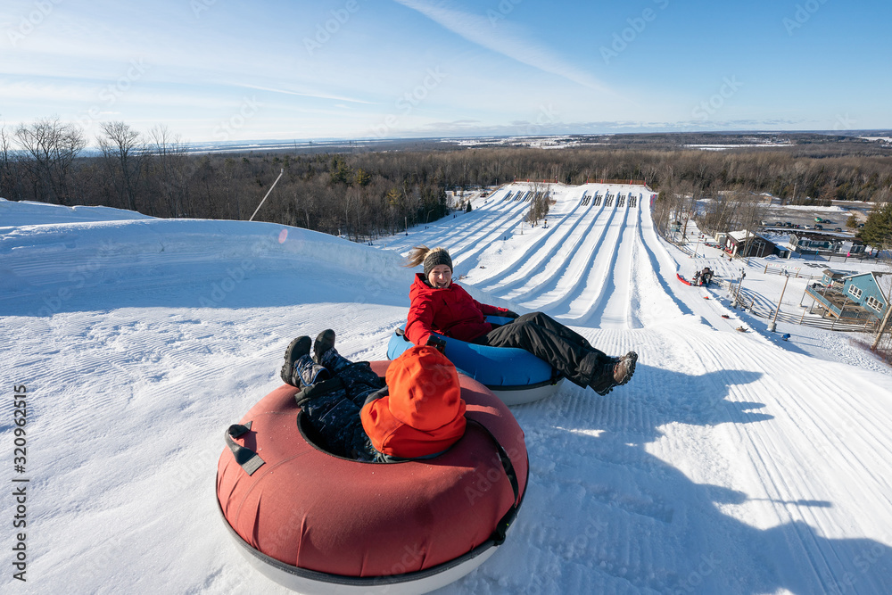 Beautiful woman snow tubing with her son in the winter in Canada