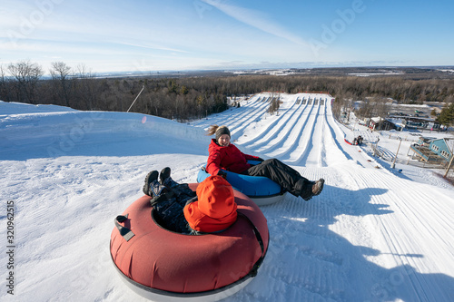 Obraz na płótnie Beautiful woman snow tubing with her son in the winter in Canada w salonie