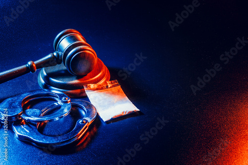 Fototapete Judge gavel, handcuffs with white powder bag on dark table