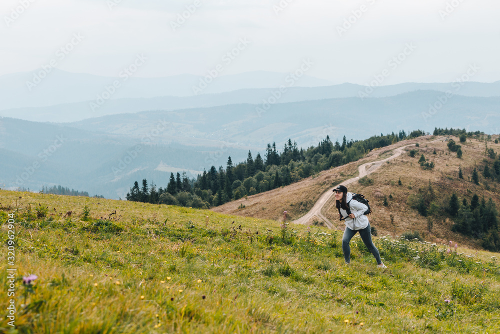 woman with backpack hiking in mountains