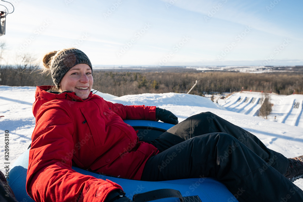 Beautiful woman snow tubing in the winter in Canada