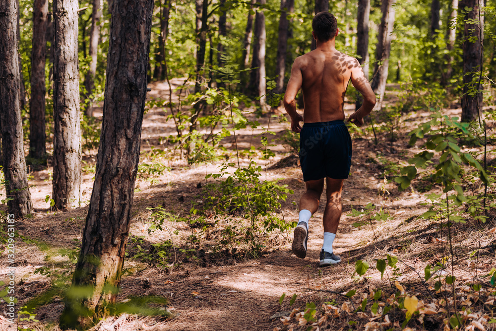 Healthy shirtless running runner man workout on forest trial Healthy shirtless running runner man workout on forest trial