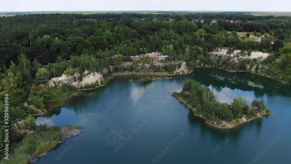 Aerial View of lake with Beautiful Water in a Quarry Surrounded by Forest Tracking Backward Revealing Small Town and Mining Operation Aerial View of lake with Beautiful Water in a Quarry Surrounded by Forest Tracking Backward Revealing Small Town and Mining Operation
