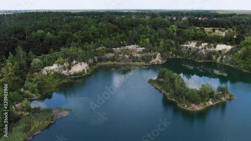 Aerial View of lake with Beautiful Water in a Quarry Surrounded by Forest Tracking Backward Revealing Small Town and Mining Operation photo