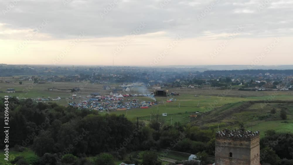 Aerial View of Music Festival in a Field in the Distance Flying Over Castle in Europe Aerial View of Music Festival in a Field in the Distance Flying Over Castle in Europe