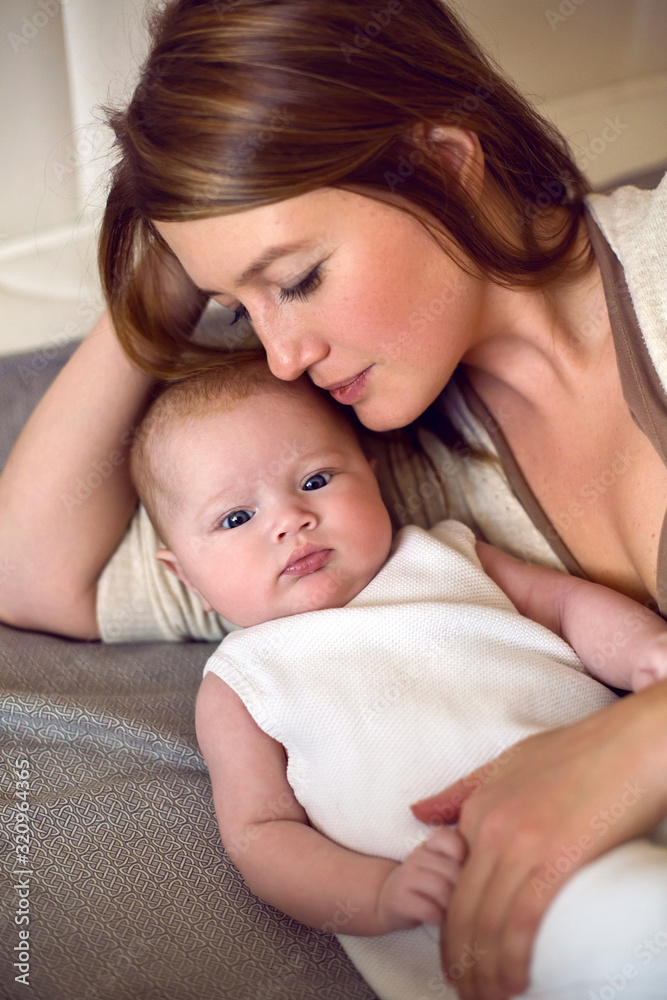 young mother with red hair is lying on the bed with her daughter young mother with red hair is lying on the bed with her daughter