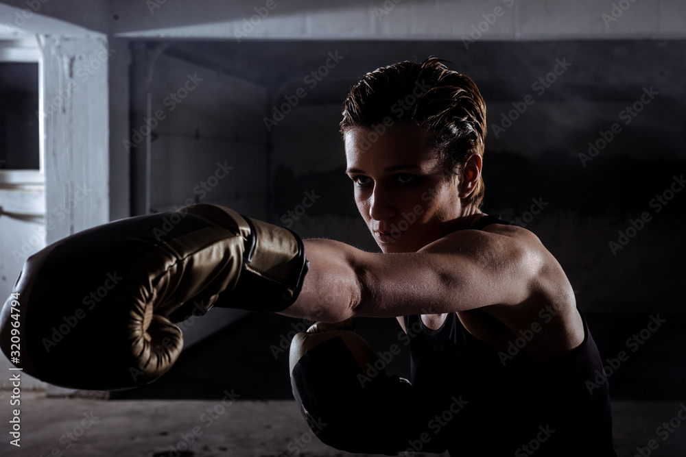 Side view of a silhouette female fighter punching with boxing gloves