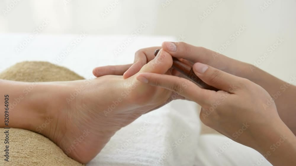 Therapist giving Thai foot massage with stick to a woman in spa Therapist giving Thai foot massage with stick to a woman in spa