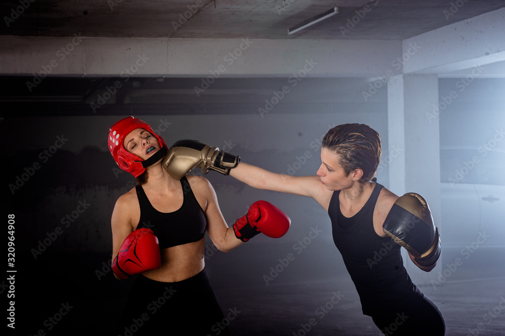 Two professional female boxers punching each other in aggressive garage boxing fight