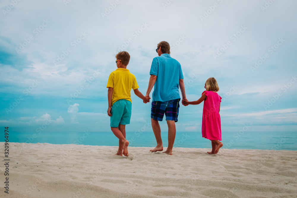 father with son and daugther walking on beach father with son and daugther walking on beach