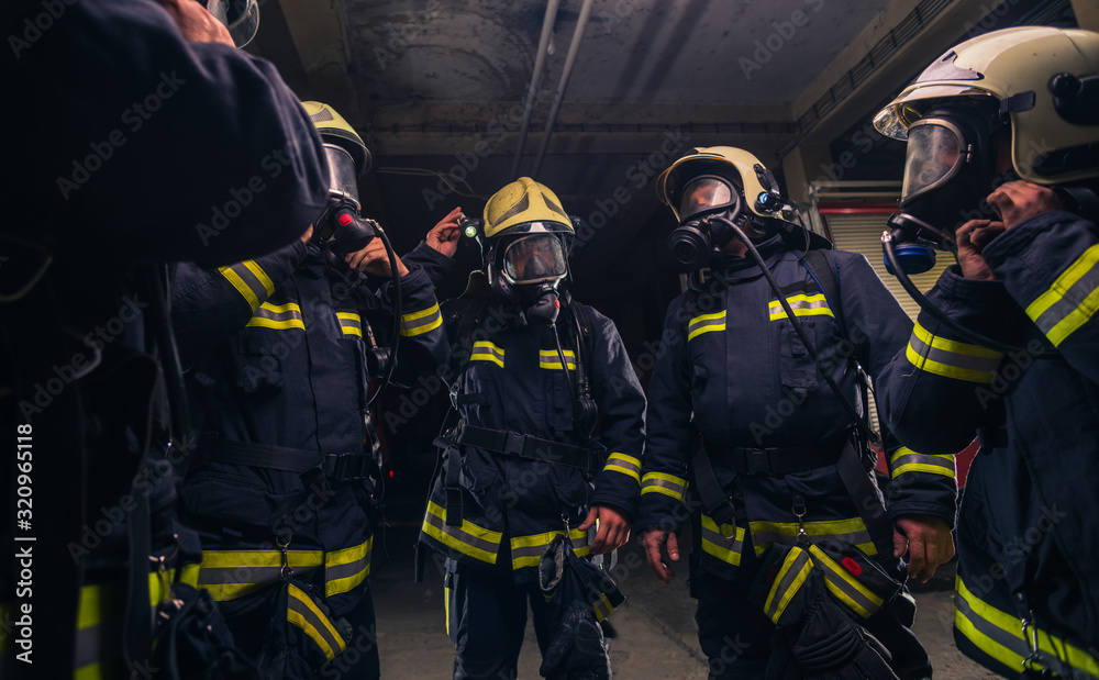 Fototapeta premium Team of firefighters in the fire department wearing gas masks and uniform