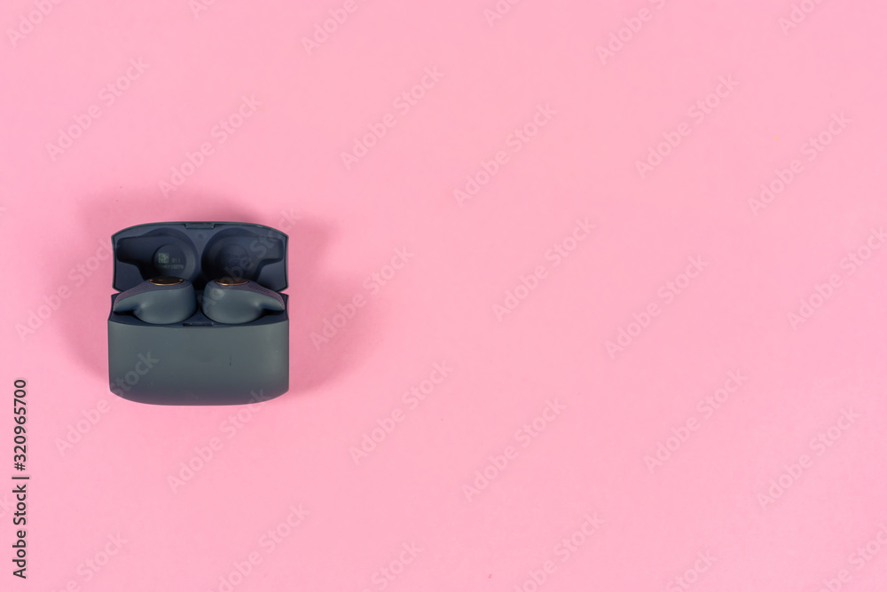 Wireless headphones on pink table with background Wireless headphones on pink table with background