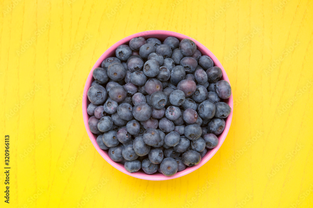 blueberries in pink bowl on yellow table blueberries in pink bowl on yellow table
