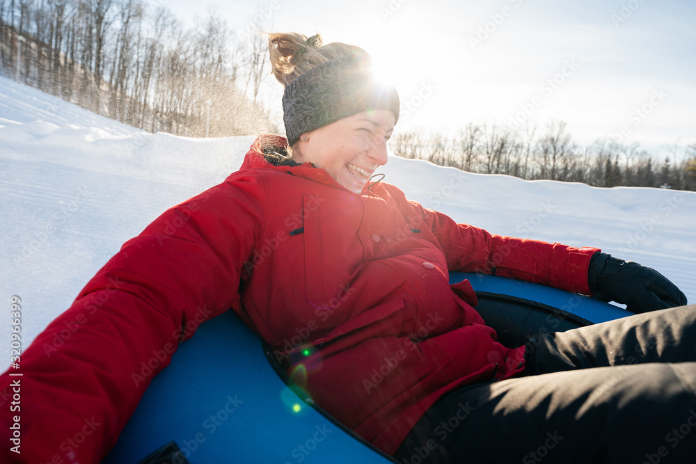 Beautiful woman snow tubing in the winter in Canada