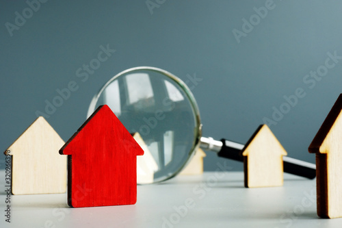 Home worth and property value concept. Magnifying glass and model of house. photo