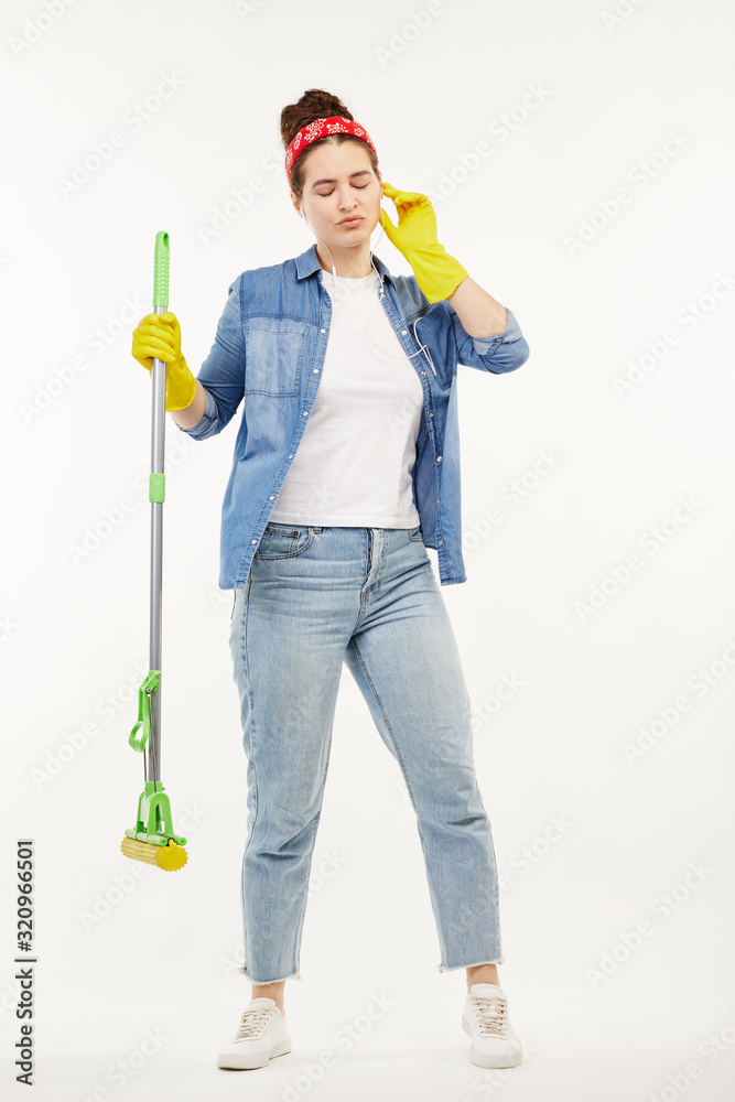 Pretty woman in work-wear holds a green mop and dances. Pretty woman in work-wear holds a green mop and dances.