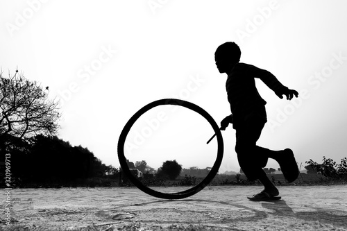 Bangladesh – January 24, 2020: A restless boy is playing on the village road with old discarded tires at Savar, Dhaka, Bangladesh. photo