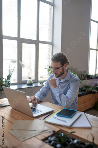 Attentive man with glasses looking at laptop.
