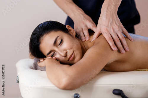 A young woman gets a massage procedure. Masseur makes back massage.