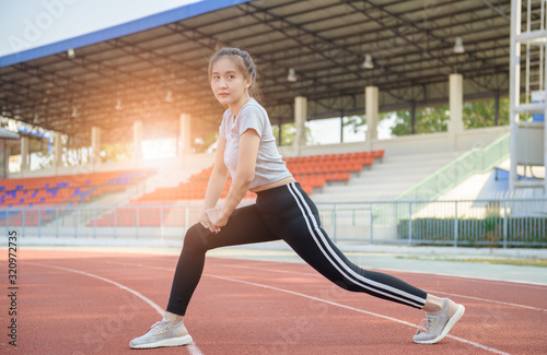 Cute sport woman stretching warm up before running on track,