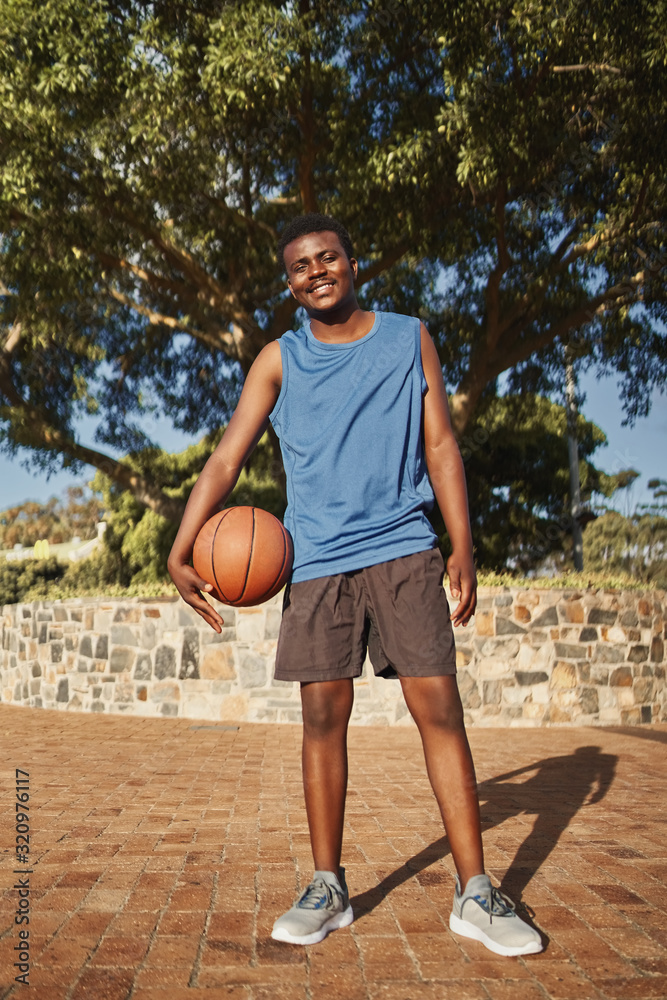 Active smiling portrait of a basketball player standing in front of tree at park Active smiling portrait of a basketball player standing in front of tree at park